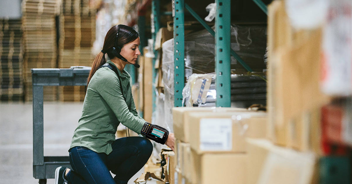 Woman in the warehouse picking packages using voice picking technology